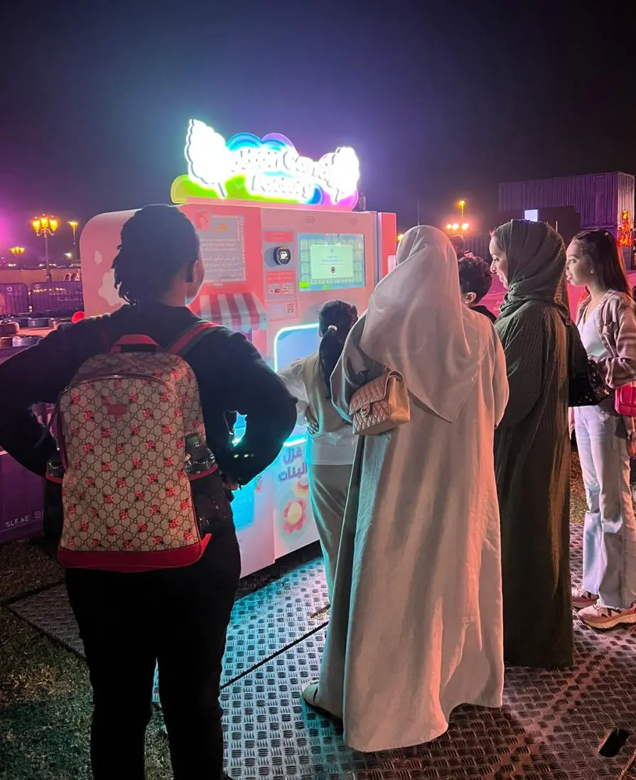 Children watching a fully automatic cotton candy machine in an arcade
